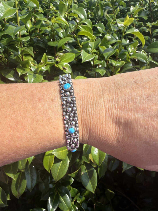 Turquoise & Sterling Silver link dot bracelet featuring bright polish silver and small turquoise stones on wrist